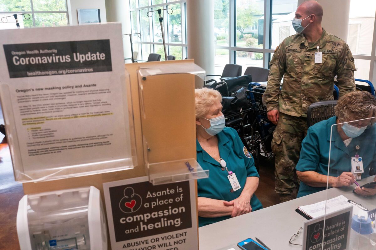 GRANTS PASS, OR - SEPTEMBER 09: (EDITOR'S NOTE: EDITORIAL USE ONLY.) An Oregon National Guardsman works with hospital staff at an intake station at Three Rivers Asante Medical Center on September 9, 2021 in Grants Pass, Oregon. Like many hospitals in the state, Three Rivers Asante is facing their largest COVID-19 surge of the pandemic, forcing them to operate well above capacity. (Photo by Nathan Howard/Getty Images)