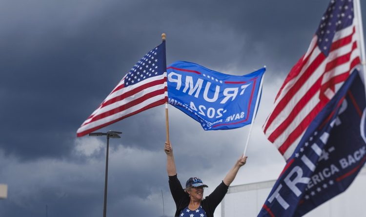 epa10714263 A supporter of former US President and Republican presidential candidate Donald J. Trump (not pictured), holds flags while waiting for Trump's arrival for the opening of his campaign headquarters in Manchester, New Hampshire, USA, 27 June 2023. EPA/CJ GUNTHER