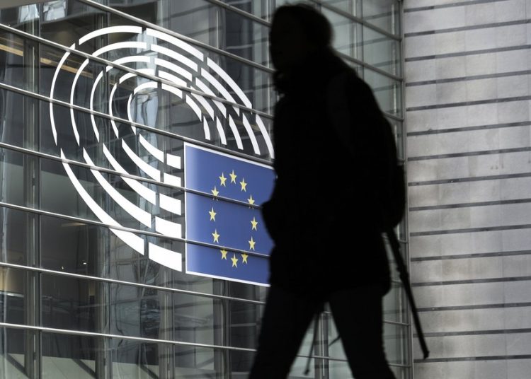 epa06418376 A man walks in front of the European Parliament building with the logo of the parliament, in Brussels, Belgium, 05 January 2018.  EPA/OLIVIER HOSLET